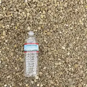 close up river rock pea gravel texture with plastic bottle for scale